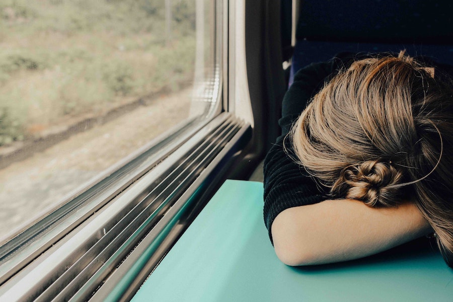 Woman with her head down on a table riding a train