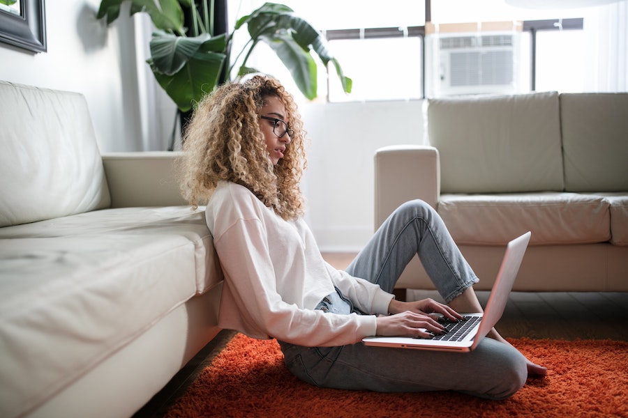 African American woman sitting on floor and working on laptop
