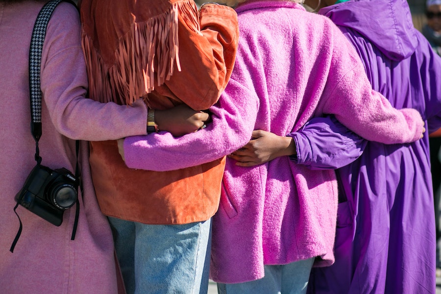 Four people wearing colorful jackets with arms around each other